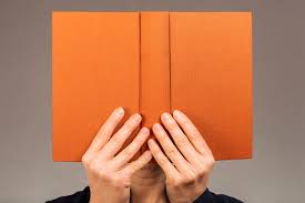 Person hiding behind book