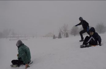 An image of Kevin, Tricia, and Logan sledding down a hill.